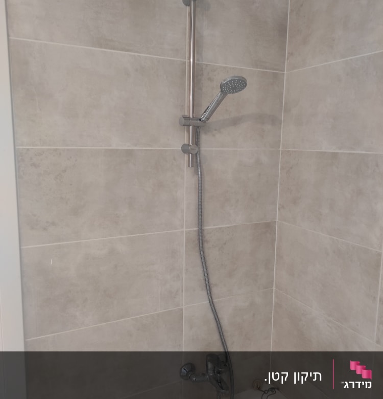 מקלחת עם ראש טוש ומוט מתכת על קיר אריחים